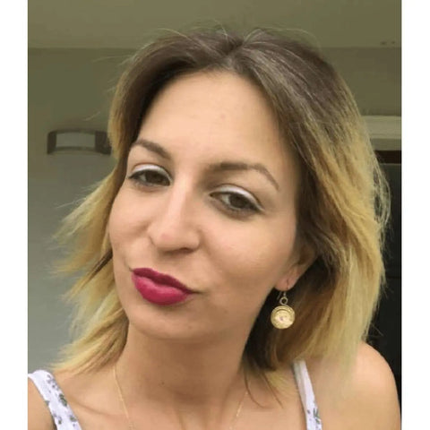 A woman with shoulder-length blonde hair and bright pink lipstick wears Alexa Martha Designs Gold Filled 14CT Crystal Spiral Earrings and a white top, posing against a neutral, blurred background.