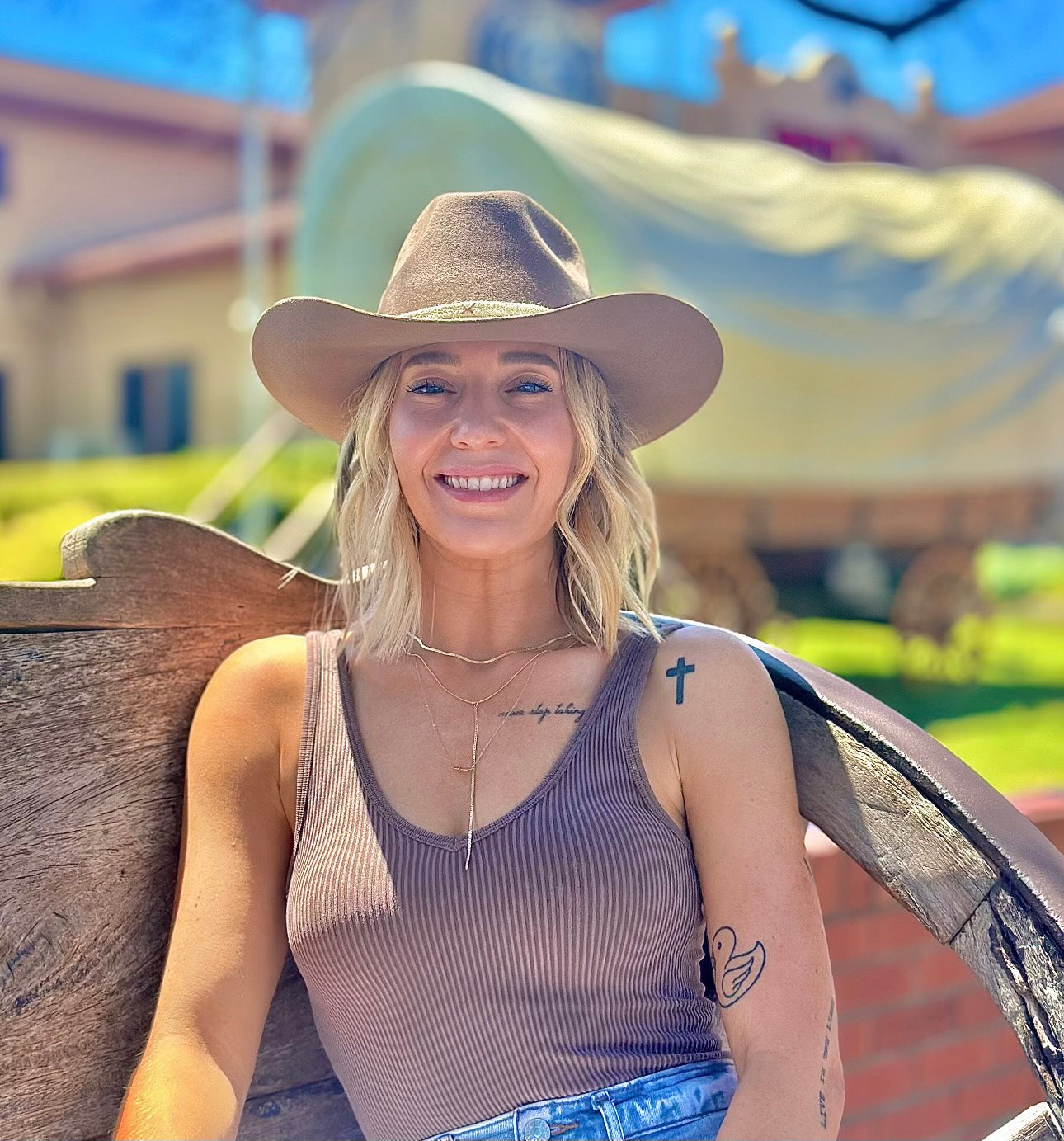 Woman wearing a cowboy hat sitting on a wooden bench with a scenic background