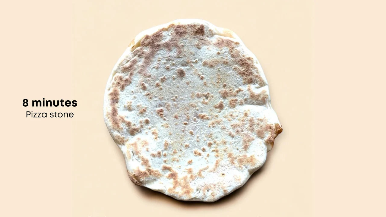 Pizza stone with a baked pizza crust on a beige background