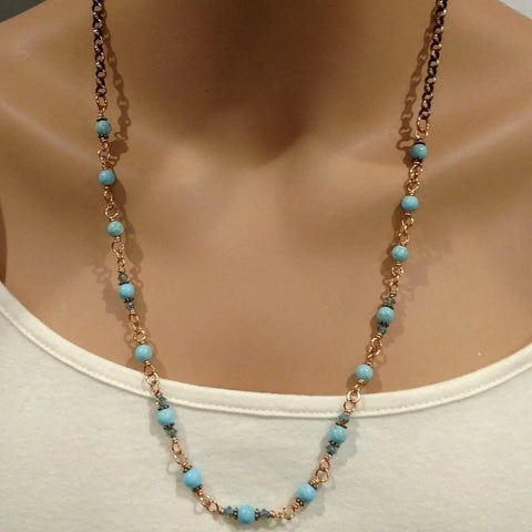 A mannequin wears the Alexa Martha Designs Wire Wrapped 24-Inch Copper Turquoise Necklace, featuring small beads linked by copper wire, paired with a white top.