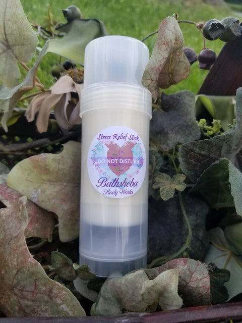 A clear tube labeled Moisture Balm - Do Not Disturb (Relief Stick) by Bathsheba Body Works sits among green and brown leaves, emphasizing a natural way to support stress relief.