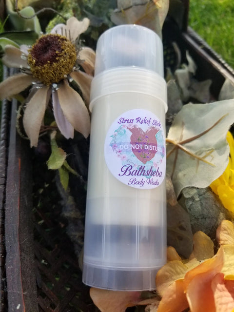 A clear container labeled Moisture Balm - Do Not Disturb (Relief Stick) by Bathsheba Body Works sits among artificial flowers and greenery in a basket outdoors—ideal for anyone seeking natural relief with calming essential oils.