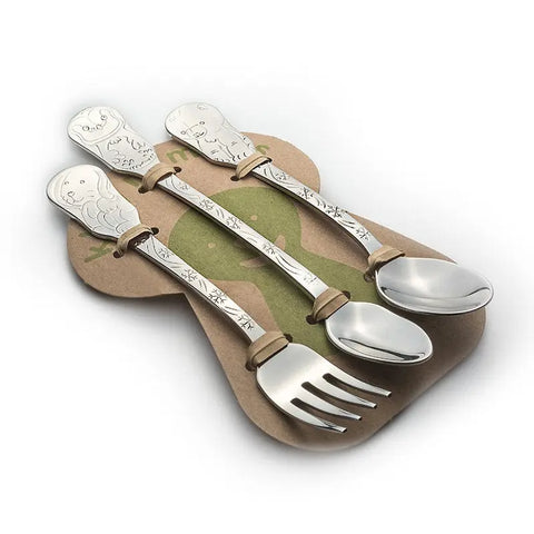 The Kleynimals 3-Piece Baby Flatware Set - Arctic Friends includes a fork, knife, and spoon with animal engravings, resting on a bone-shaped holder. This charming stainless steel set is made in the USA.