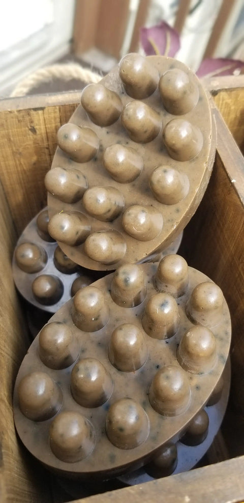 Two oval brown massage bars with raised bumps are stacked in a wooden box. Ideal for self-care, these pair perfectly with Bathsheba Body Works Hair Care - Curly Hair Shampoo for a complete natural routine.