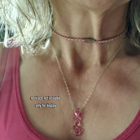 A person in a pink top showcases two necklaces: Alexa Martha Designs 3mm Bolo Leather Snap Off Choker and a silver chain with pink gems. Text on image: Necklace not included, for display only.