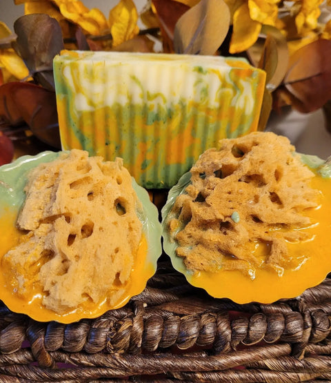 Bathsheba Body Works All Natural Soap - Ginger Turmeric (Herbal Soap) is displayed with wavy green, yellow, and white handcrafted soap bars and natural loofah soaps in a woven basket with autumn leaves in the background.
