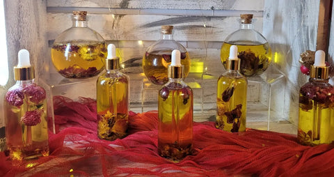 A display of Bathsheba Body Works Body Oil - XO in decorative glass bottles with droppers, filled with organic Abyssinian and argan blends, arranged on a red cloth and highlighted by warm string lights.