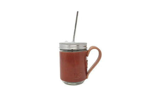 The Urban Southern Mason Jar Mug features a clear glass body, silver lid, metal straw, and a brown leather-wrapped sleeve with handle, combining vintage charm with modern style against a white background.
