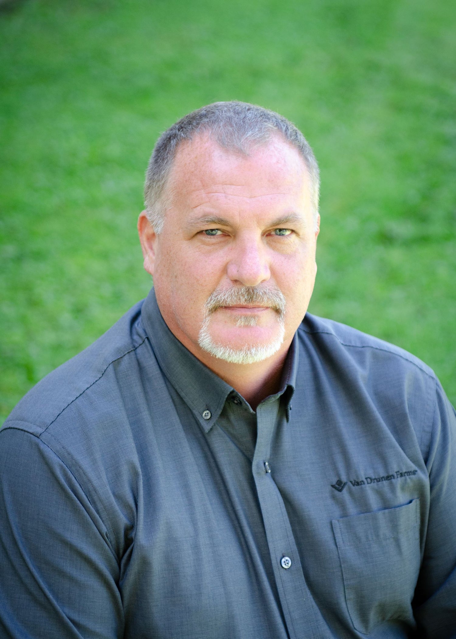Man wearing a dark shirt with a logo against a green background