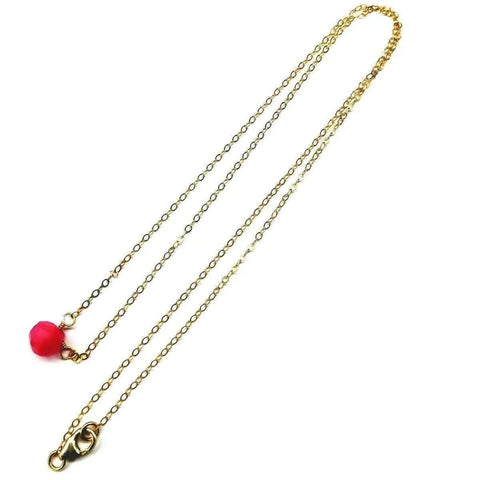 The Tiny Hot Pink Chalcedony Gold Filled Necklace by Alexa Martha Designs features a single small hot pink chalcedony bead near the lobster clasp, set on delicate 14 kt gold filled chain and displayed on a white background.
