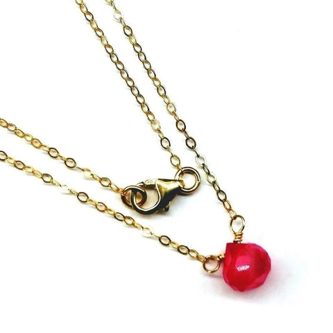 The Tiny Hot Pink Chalcedony Gold Filled Necklace by Alexa Martha Designs features a single faceted pink chalcedony pendant on a delicate 14 kt gold filled chain with lobster clasp, elegantly displayed on a white background.