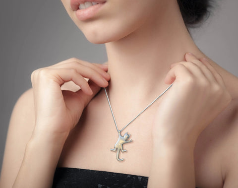 A woman in a strapless black top adjusts the Solid Sterling Silver Cat Necklace Style #1 by Skinny Petes Gourmet Catnip, featuring a playful cat pendant—ideal cat lover jewelry—against a plain gray background.