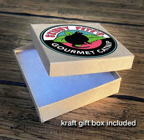 A small kraft gift box with a Skinny Petes Gourmet Catnip sticker on the lid, slightly open on wood. Perfect for gifting the Solid Sterling Silver Cat Necklace Style #1 by Skinny Petes Gourmet Catnip. Text: kraft gift box included.
