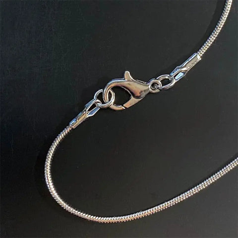 A close-up of Skinny Petes Gourmet Catnip Solid Sterling Silver Cat Necklace Style #1 with a snake chain and lobster claw clasp, handcrafted in the USA, displayed on black—ideal for cat lover jewelry collections.