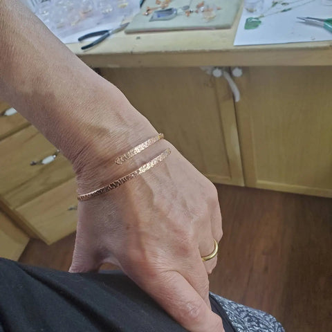 A hand adorned with Alexa Martha Designs Adjustable Hammered Copper Overlap Bangle for Him or Her.