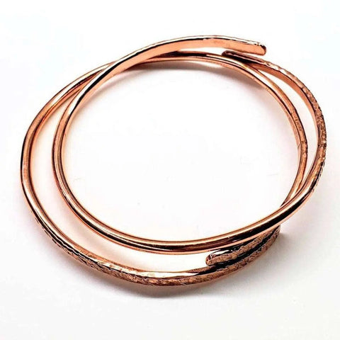 The Adjustable Hammered Copper Overlap Bangle for Him or Her by Alexa Martha Designs is a handmade, spiral copper bracelet with a hammered texture, combining elegance and versatility in an open circle design.