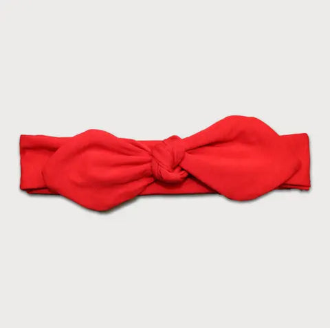 The Goodnighties Knotted Bow Headband, in vibrant red with a large central knot, is handmade in the USA and shown against a plain light gray background.