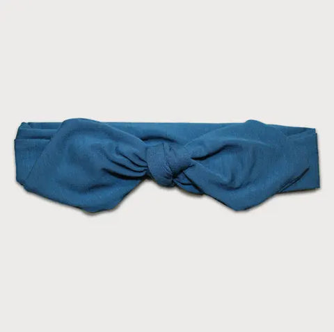 The Goodnighties Knotted Bow Headband is a blue, handmade accessory from the USA, featuring a central knot and shown on a plain white background.