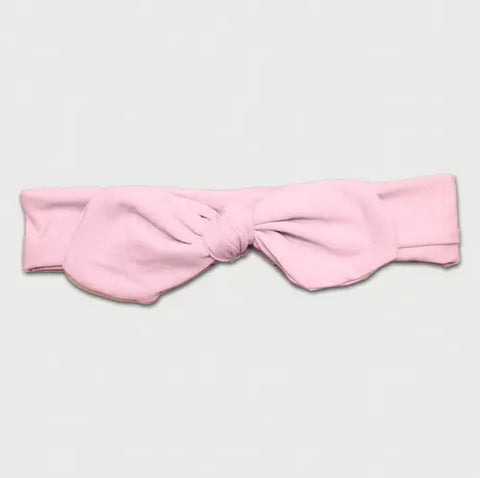 The Goodnighties Knotted Bow Headband in light pink is handmade in the USA and adds a charming, stylish touch. Photographed on a plain light background.