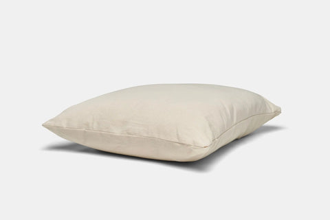 The Natural Cotton Pillow With Wool Filling by American Blossom Linens, shown against a white background, features a cream-colored rectangular design—perfect for multi-position sleepers seeking comfort and support.