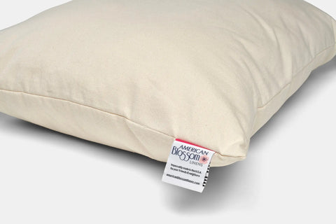 The Natural Cotton Pillow With Wool Filling by American Blossom Linens, shown in cream with a visible branded corner tag, is customizable and ideal for multi-position sleepers against a plain white background.
