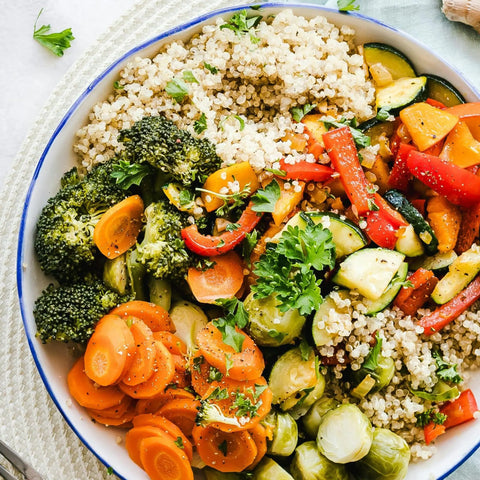 A bowl of non-GMO quinoa, steamed broccoli, carrots, Brussels sprouts, and roasted veggies is garnished with fresh parsley and Gustus Vitae’s Air Fryer Ultimate Veggies Seasoning Set artisanal spice blends.