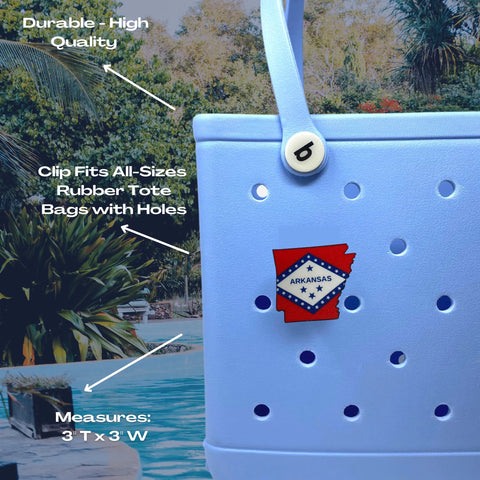 A light blue rubber tote sits poolside, adorned with a red USA Flag Boglets charm by Chatelet Manufacturing. The charm fits most totes, adds patriotic flair, is durable, and measures 3 tall by 3 wide.