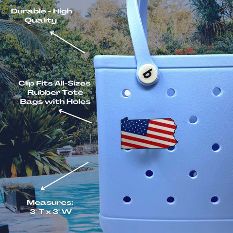 A blue rubber tote by a pool displays a Chatelet Manufacturing Boglets USA Flag Charm in Pennsylvania shape, compatible with Bogg Bags and Simply Southern totes. This 3x3 high-quality charm shows patriotism and fits all standard bag holes.