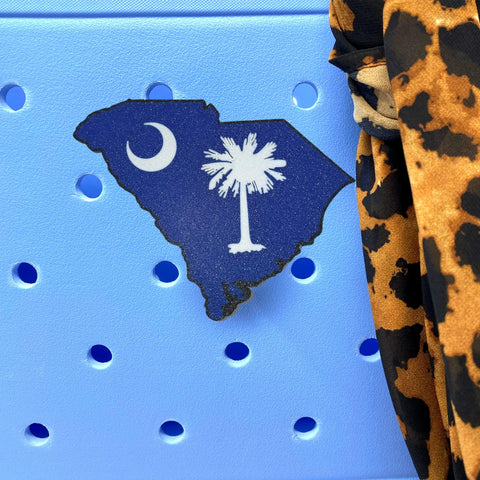 Showcase your patriotism with Chatelet Manufacturing’s Boglets USA Flag Charm on a blue background featuring a South Carolina cutout, white palmetto tree, crescent moon, and leopard print—perfect for Bogg Bags and compatible totes.