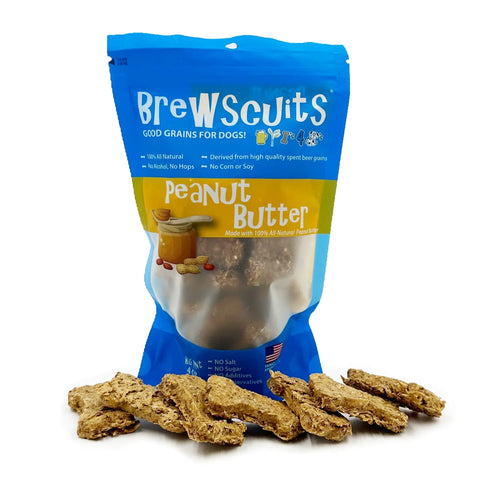 A blue and yellow bag of Brewscuits Half Pints Peanut Butter dog biscuits stands upright, with several bone-shaped treats in front. The packaging notes upcycled grains and no corn, soy, salt, or sugar.