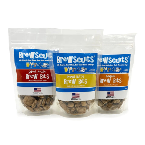 Three bags of Brewscuits Brew Bits—Sweet Potato, Peanut Butter, and Pumpkin—stand upright in a row. Each bag has a clear window revealing the natural dog treats inside and sports a vibrant label.