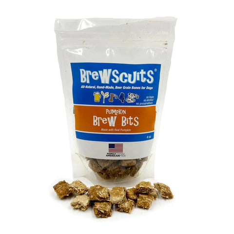 A bag of Brewscuits Brew Bits dog treats, made from spent grain, sits behind several square brown treats. The clear package has blue and orange labels with dog and beer glass icons—natural treats perfect for your pup!.