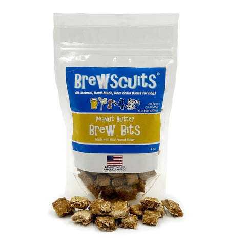 A clear bag labeled Brewscuits Brew Bits with small brown spent grain dog treats inside and some scattered in front. The packaging highlights these all-natural dog treats are made with real peanut butter.