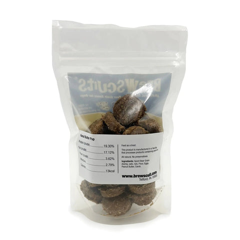 A clear resealable bag of round, brown Peanut Butter Pup dog treats by Brewscuits stands upright on a white background. The front label features nutritional info and brewscuits.com.
