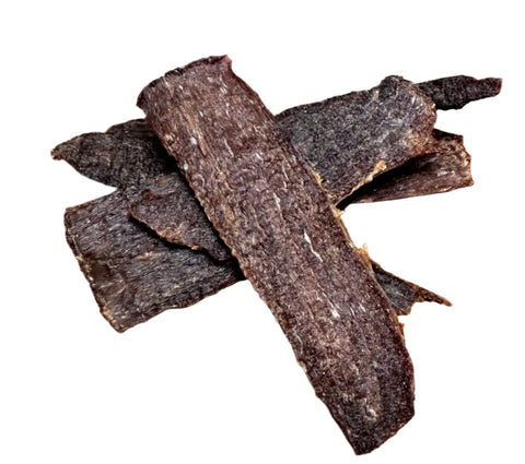 Dogtown Bakery Moo Chews—dark brown, grass-fed beef jerky for dogs—are stacked on a white background, offering a nutritious treat your dog will love.
