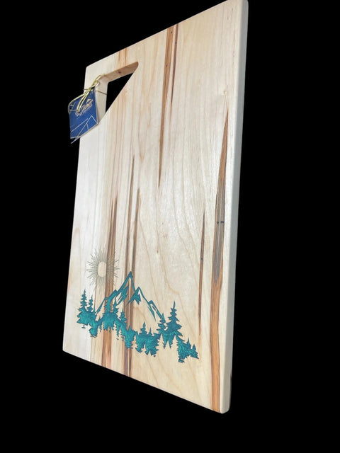 The Emerald Epoxy Inlay Ambrosia Maple Serving Tray by B. James Design & Woodwork features a triangle cut-out handle and handcrafted mountain, tree, and sun design with a striking emerald epoxy accent.