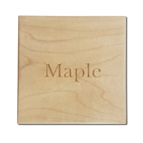A rectangular light wood sample from Legacies of America Woodworking Company, engraved Maple at the center, features a smooth surface and natural grain. Product: American Flag Challenge Coin Display - Walnut & Maple.