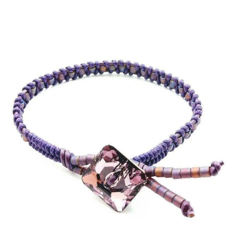 The Amethyst Braided Leather Swarovski Crystal Square Button Bracelet by Alexa Martha Designs features a faceted square Swarovski crystal and an adjustable cord with cylindrical beads—a unique piece of handmade Montana jewelry.