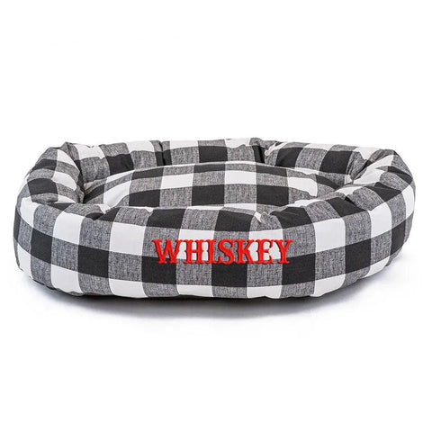 The Majestic Pet Anderson Check Bagel Bed - Personalized features a black and white plaid, water-resistant design with WHISKEY embroidered in red. Its machine washable for easy care.