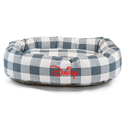 The Majestic Pet Anderson Check Bagel Bed - Personalized features a blue and white checkered design with Daisy embroidered in red script on the front. This dog bed is machine washable for easy care.