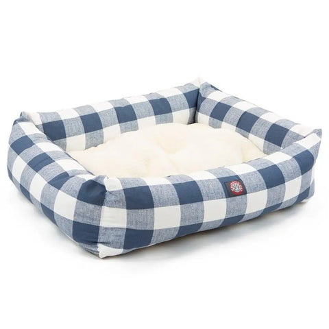 The Majestic Pet Anderson Check Luxe Bagel Bed features blue and white plaid sides, a cream faux sheepskin interior, raised edges, a red logo tag, and a machine washable slipcover for easy cleaning and comfort.