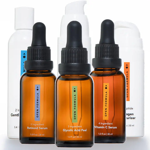 Open Formula’s Transformational Routine features three amber dropper bottles and two white pump bottles with color-coded labels for retinoid, glycolic acid peel, and vitamin C—an anti-aging skincare lineup arranged together.