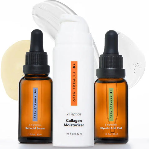 Three amber dropper bottles and a white pump bottle from Open Formulas Anti-Aging Superset are arranged with cream and serum smears in the background.