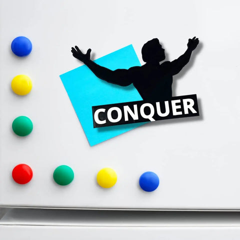 A Chatelet Manufacturing Arnold Schwarzenegger Conquer Motivational Fridge Magnet holds a blue sticky note and a triumphant silhouette on a fridge, boldly displaying CONQUER—perfect for daily inspiration at home.