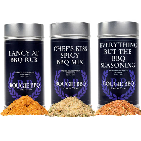 The Bougie BBQ Essentials Collection - 3 Pack by Gustus Vitae showcases three artisanal seasonings, each in front of its tin with vibrant, all-natural blends: Fancy AF BBQ Rub, Chef’s Kiss Spicy BBQ Mix, and Everything But the BBQ Seasoning.