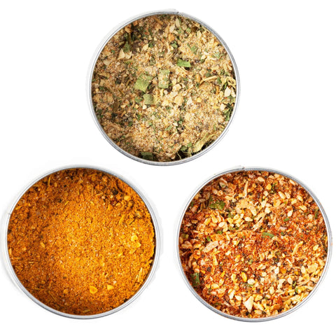 The Gustus Vitae Bougie BBQ Essentials Collection - 3 Pack features three round containers of all-natural gourmet BBQ blends in greenish, orange-yellow, and red-brown hues, arranged in a triangle on a white background.