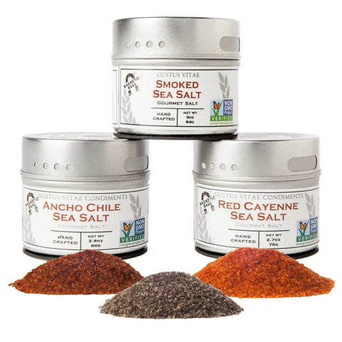 The Gustus Vitae Gourmet Grilling Salts Collection includes three tins—Smoked Sea Salt, Ancho Chile Sea Salt, and Red Cayenne Sea Salt—in sleek silver packaging. A perfect gift for any culinary enthusiast.