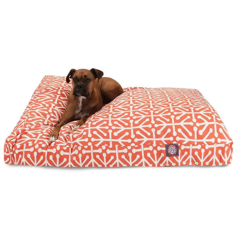 A brown dog rests on the Majestic Pet Aruba Rectangle Dog Bed, featuring a large orange and white geometric pattern and premium polyester fiber fill for ultimate softness and comfort.