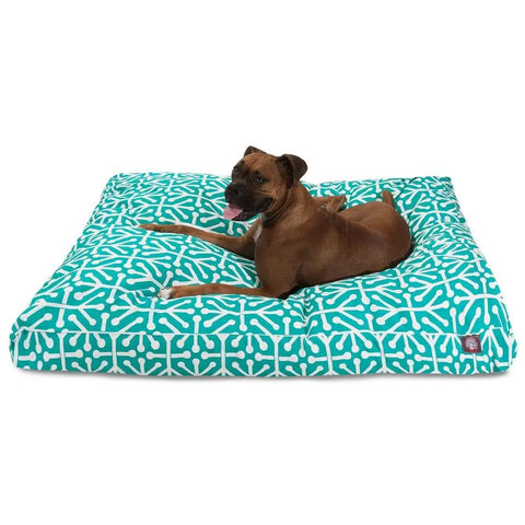 A brown dog lies alert on the Majestic Pet Aruba Rectangle Dog Bed, featuring a teal and white pattern and a machine washable cover.