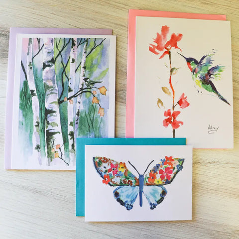 The JuLu Cards Assorted Card Bundle features three greeting cards—a birch trees design, a hummingbird with red flowers, and a butterfly with floral patterns—perfect for any occasion or to enhance your birthday cards pack.